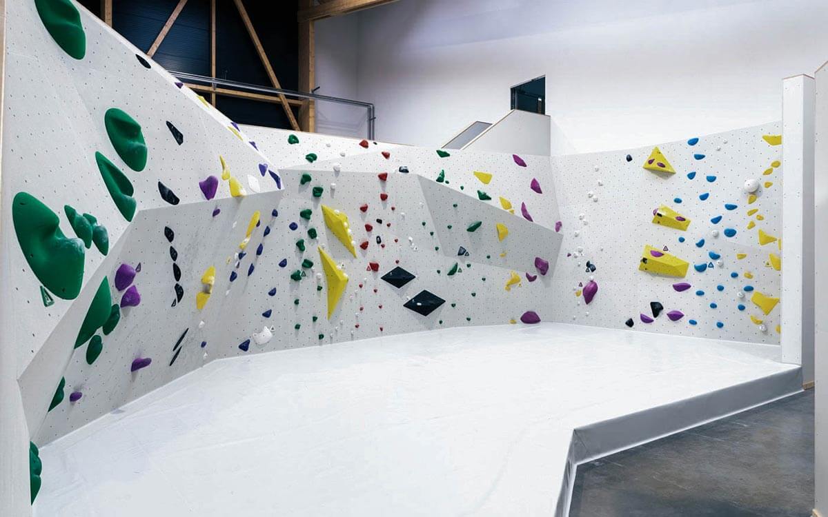 Niedrige Boulderwände mit bunten Griffen und Routen für verschiedene Schwierigkeiten.