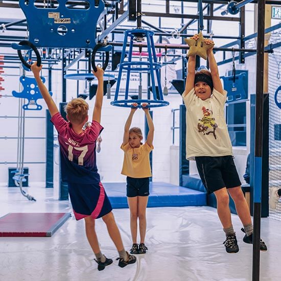 Kinder hängen an Hindernissen im Ninja-Parcours des Stuntwerks. Spaß, Bewegung und Geschicklichkeit bei den Kidsmoves