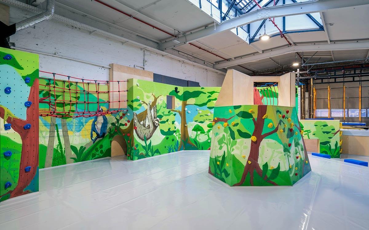 Heller Indoor-Kletterbereich für Kinder mit Hängebrücke und farbenfroher Dschungelgestaltung im Stuntwerk Krefeld.