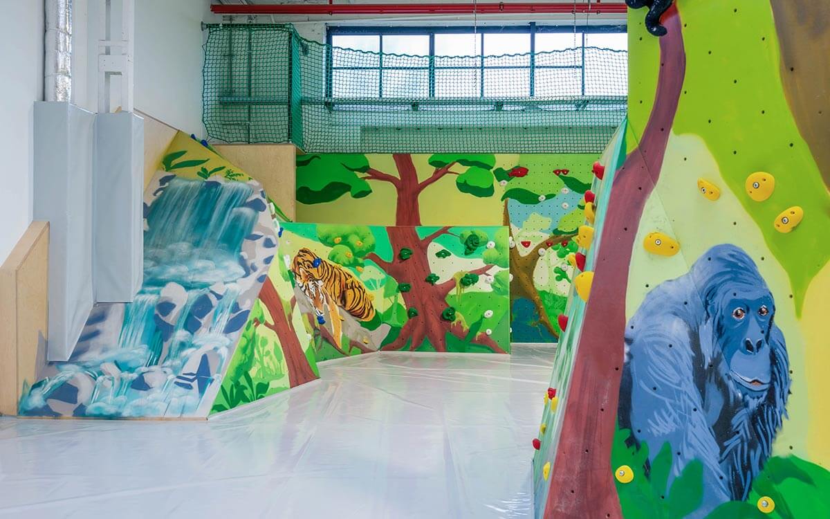 Bunt bemalter Kinderbereich mit Dschungelmotiv, Kletterwänden und Tierfiguren im Stuntwerk Krefeld – perfekt für kleine Abenteurer:innen.