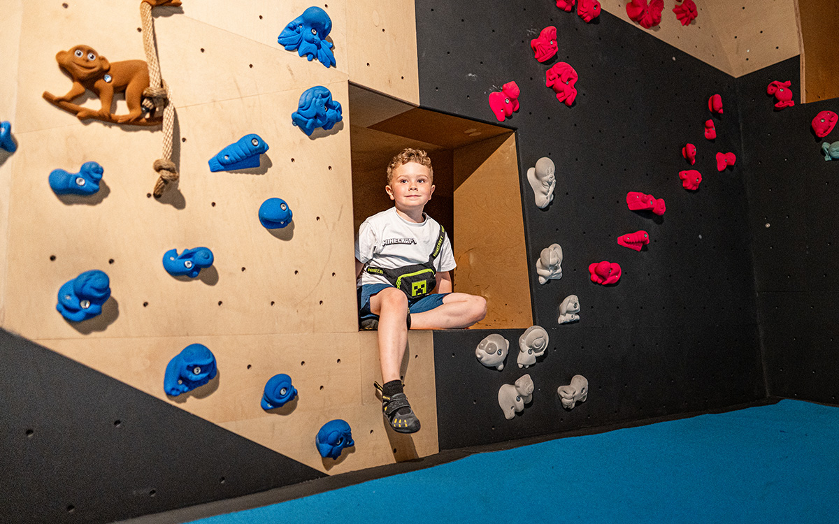 Kind im Kinderboulderbereich des Stuntwerk Trostberg mit bunten Klettergriffen