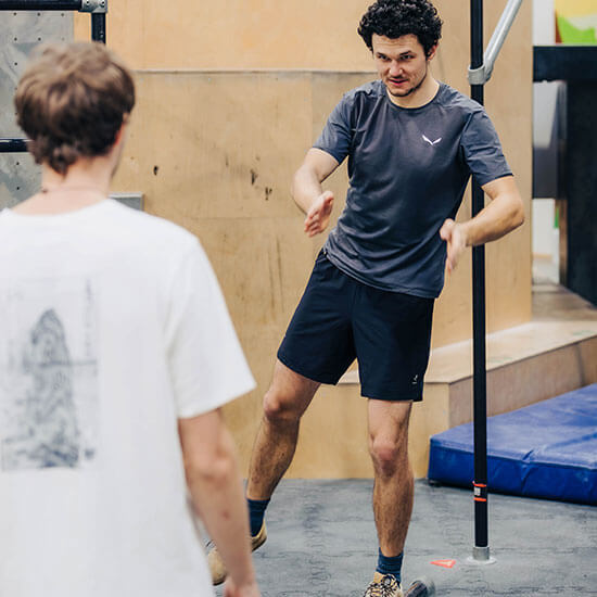 Trainer erklärt eine Parkour-Übung in der Halle und zeigt Bewegungsabläufe mit den Händen