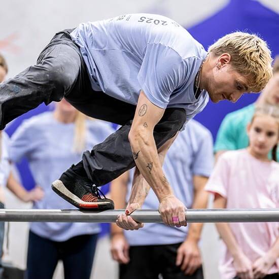 Sportler überwindet im Stuntwerk eine Metallstange mit einem kontrollierten Parkour-Move. Er trainiert Kraft, Balance und saubere Technik bei der Hindernisüberwindung.