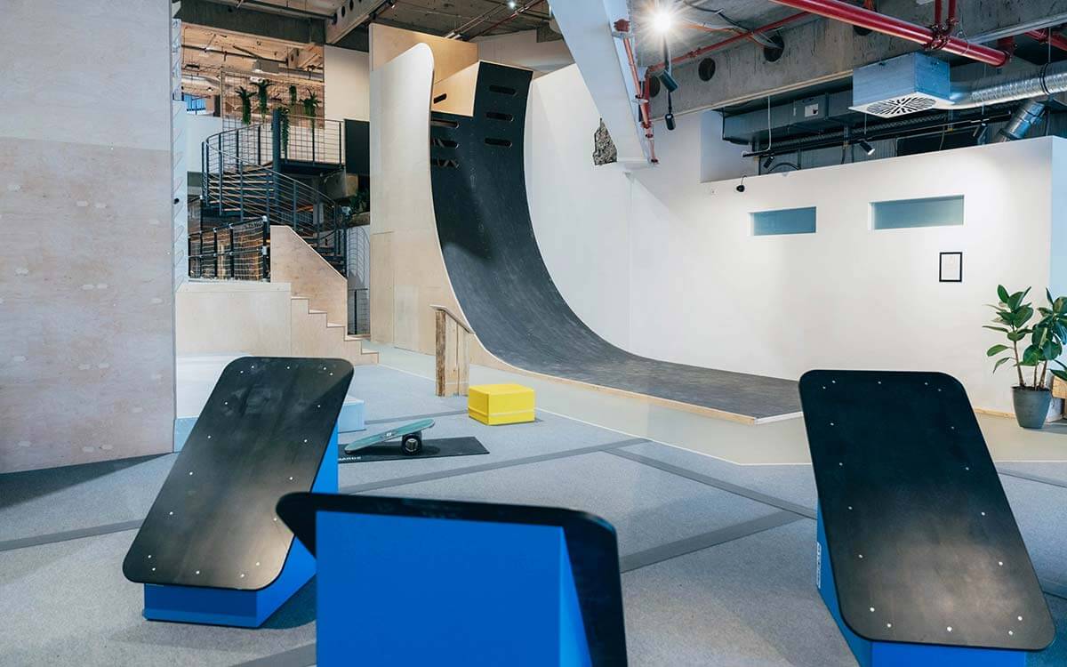 Steile schwarze Mega-Wall im Stuntwerk Troisdorf mit Holzelementen, Treppen und Balance-Boards. Trainingsbereich für Ninja Warrior-Challenges und Parkour-Bewegungen.