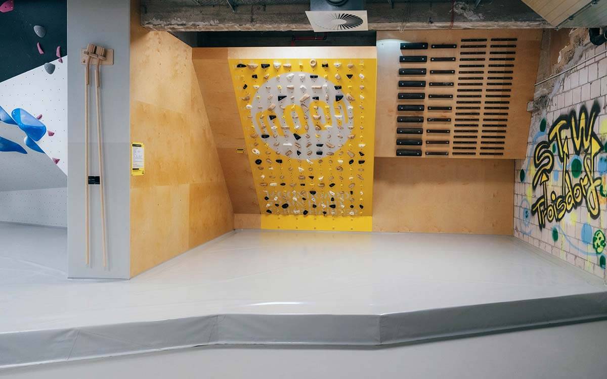 Moonboard und Campusboard mit gelber Trainingswand im Stuntwerk Troisdorf. Graffiti-Wand mit STW-Schriftzug und Holzelemente schaffen urbanes Trainingsambiente.