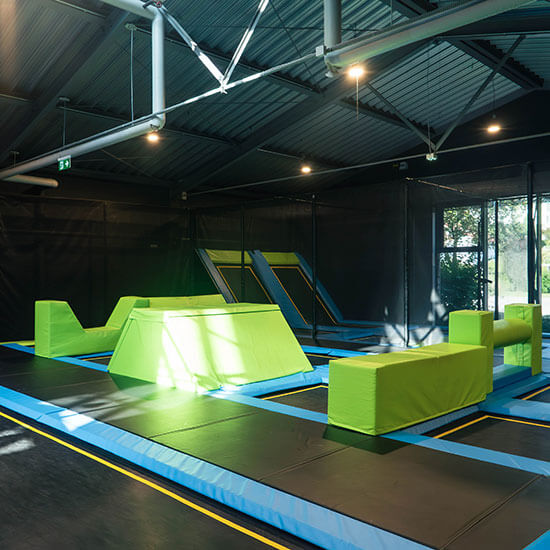 Trampolinpark mit schrägen Absprungflächen, gepolsterten Hindernissen und großzügiger Sprungzone für Kinder, Jugendliche und Erwachsene.